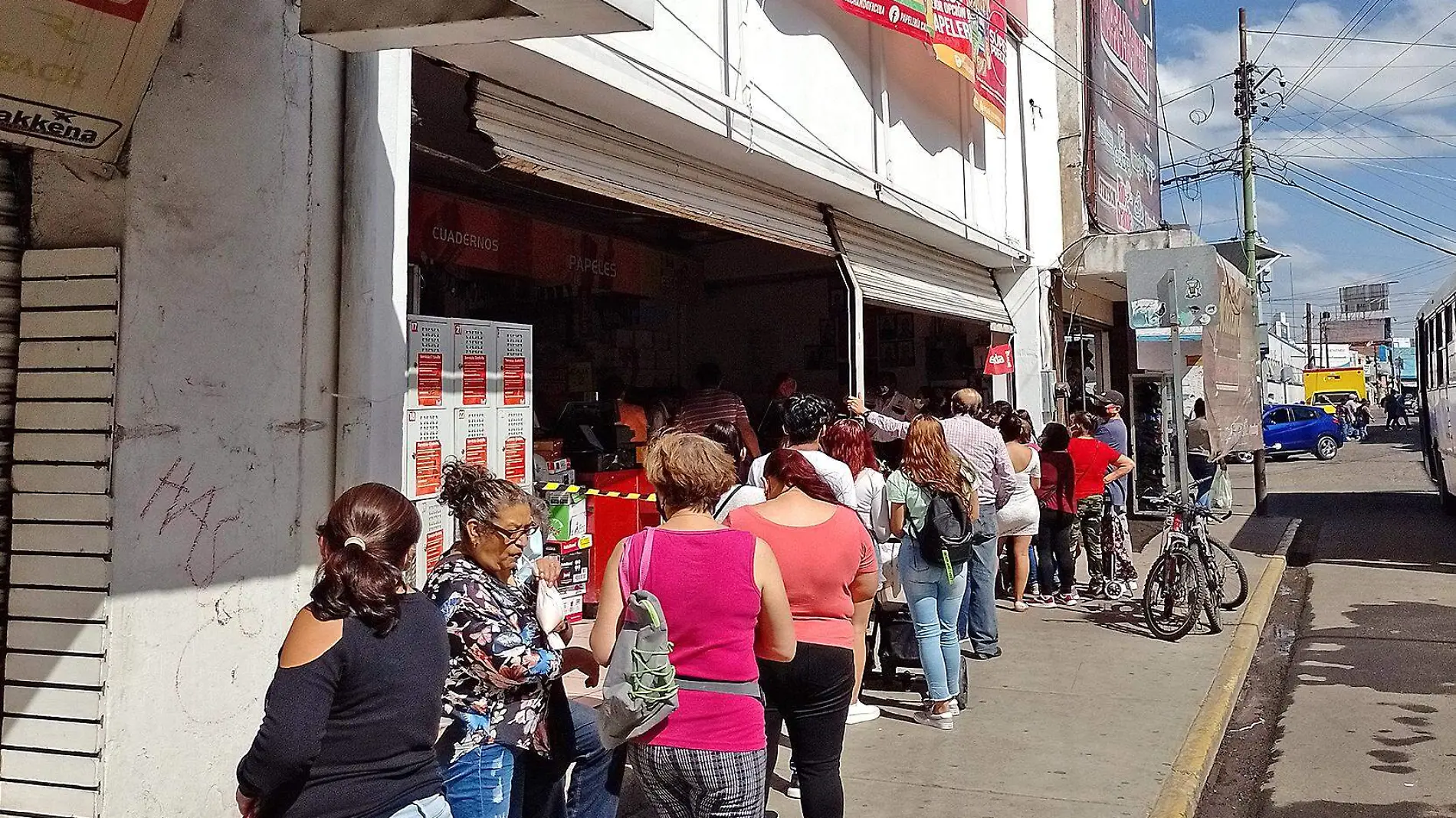 personas hacen fila afuera de papeleria